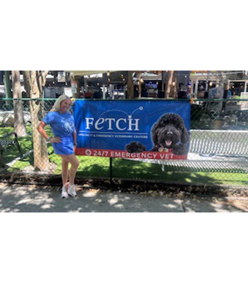 female staff member posing in front of Fetch Vets sign hung up on fence