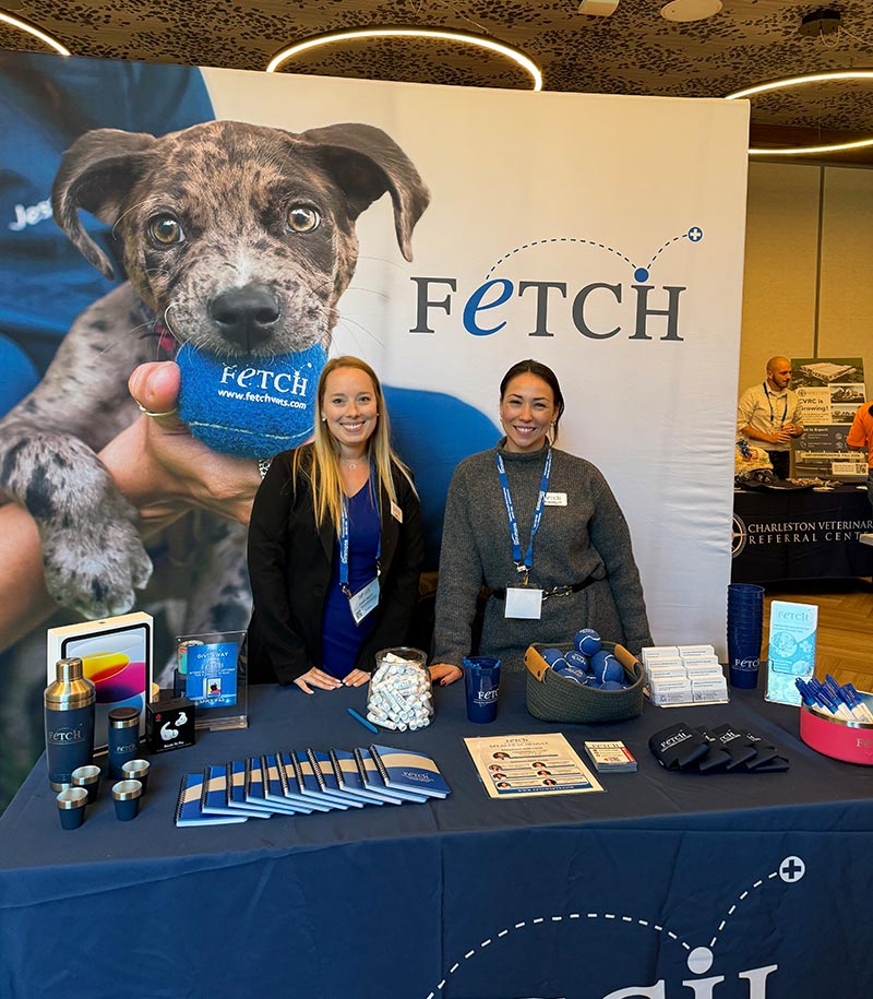 female staff members posing behind table in display booth