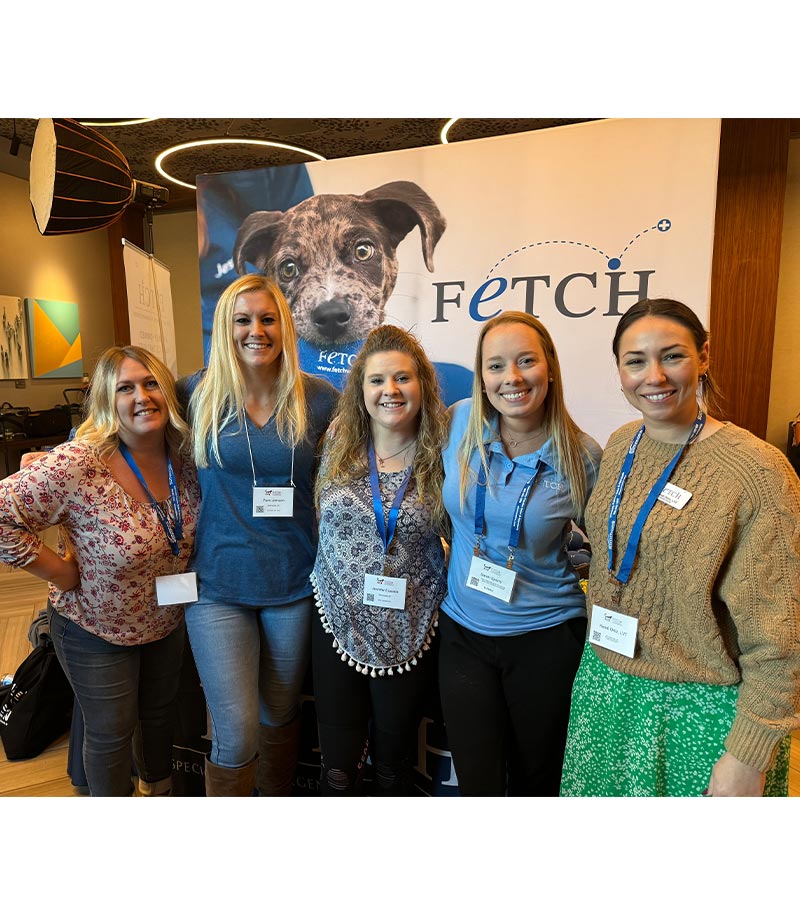 five female staff members posing in front of display booth