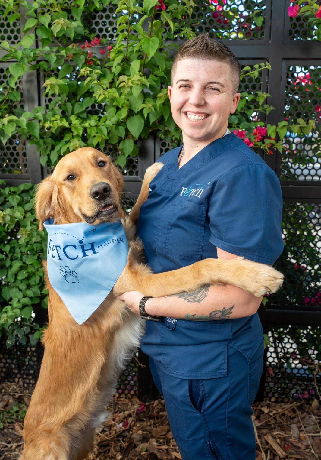Staff Member Smiling And Posing With Golden Retriever staff member smiling and posing outdoors with golden retriever wearing a Fetch Vets bandana